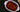 Top down image of a white baking dish with an assortment of enchiladas, smothered in a homemade red sauce, and topped with cheese and cilantro. Next to the dish is a wooden serving spoon and scattered dried chilis.