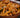 Close up of a wooden bowl with penne pasta coated in a creamy and zesty Cajun cream sauce, with chunks of juicy and Cajun seasoned Halal chicken breast and strips of red bell peppers, green bell peppers, and yellow onion.