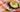 A plate of white rice topped with a savory sauce, juicy Halal burger patties, and a sunny side up egg and sprinkled with savory green onion.