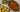 Top down image of a bowl of cooked and seasoned cabbage with chopped red pepper, onion, Halal ground lamb and sliced beef franks. Served with mixed vegetables and cornbread.