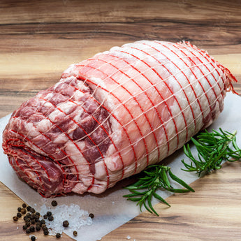 Raw meat roll on a wooden cutting board with herbs and spices