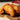 Crispy golden-brown fried chicken tenders stacked on a dark slate serving board, with a small white bowl of ketchup in the background.