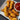 Crispy golden-brown fried chicken tenders served on a white square plate with a small white ramekin of red ketchup, set on a dark textured surface.