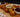 A serving board with an assortment of golden-brown fried thanksgiving leftover balls stuffed with turkey, stuffing, and mashed potatoes next to dishes of cranberry sauce and brown gravy.