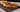 A tortilla wrap of beef, cheese, lettuce, tomato, and sour cream sliced in half and stacked in front of more golden-brown crunchwraps, all served on a black wood serving board.