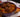 An ornate purple bowl with stir-fry of cooked soba noodles, red peppers, cabbage, sliced carrots, and onion, coated in a brown stir-fry sauce and topped with 3 juicy Halal meatballs sprinkled with sesame seeds.