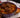 An ornate purple bowl with stir-fry of cooked soba noodles, red peppers, cabbage, sliced carrots, and onion, coated in a brown stir-fry sauce and topped with 3 juicy Halal meatballs sprinkled with sesame seeds.