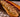 A black serving board with a long deli loaf of bread filled with savory gravy and stuffing, tender shredded Halal turkey, and tangy homemade cranberry sauce.