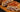 A wood serving board with a large chicken bake, sliced in half and stacked, stuffed with Halal chicken, Halal diced beef bacon, and creamy sauce all wrapped in a crispy golden-brown crust and topped with crispy cheese.