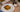 Top down image of a slice of breakfast casserole made of eggs with Halal sausage, spinach, and hashbrowns baked and topped with cheese. Served on a white plate on a brown tablecloth.