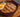 A purple decorated bowl of ramen with noodles, shredded carrots, spinach, and mushrooms in broth topped with cuts of juicy pan-fried Halal chicken and a soft boiled egg sliced in half.