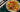 Top down image of golden brown and seasoned Halal chicken thigh resting on top of golden and tender potato slices and chunks of red bell pepper. Served on a gray plate on a dark green striped tablecloth.