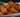 A stack of golden-brown fried Halal chicken egg rolls stuffed with shredded carrots, cabbage, aromatics, and pieces of juicy Halal chicken breast served on a white and blue ornate plate.