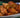 A stack of golden-brown fried Halal chicken egg rolls stuffed with shredded carrots, cabbage, aromatics, and pieces of juicy Halal chicken breast served on a white and blue ornate plate.