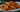 A stack of golden-brown fried Halal chicken egg rolls stuffed with shredded carrots, cabbage, aromatics, and pieces of juicy Halal chicken breast served on a white and blue ornate plate.
