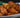 A stack of golden-brown fried Halal chicken egg rolls stuffed with shredded carrots, cabbage, aromatics, and pieces of juicy Halal chicken breast served on a white and blue ornate plate.
