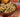 A wood bowl of tender penne pasta, chunks of Halal chicken, and broccoli and coated in richly creamy homemade alfredo sauce. Served alongside garlic bread.