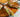 A Wood platter of Spring rolls made with carrot, cucumber, lettuce, mint, Halal chicken, and rice noodles rolled up in rice paper wraps. Served with creamy peanut sauce and savory pepper sauce.