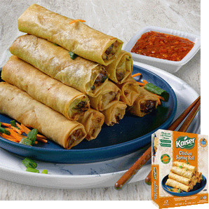 A pyramid of 10 crispy fried spring rolls sits on  plate with a small pile of sliced carrots to the left. To the right and behind the pyramid is a small square bowl of chili paste. Over the image is a box of Kaiser Chicken Spring Rolls. 