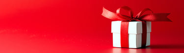 a red background with a white box on the right hand side. The box is wrapped with red ribbon that is tied into a bow