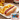 A grilled midamar jumbo campfire griller in a bun with bbq sauce. Beside it rests a small pile of french fries and a tea. In the right hand corner is an image of a package of the product