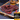 Midamar halal beef jerky strips sit on a cutting board surrounded by dried peppers and seeds, behind the jerky is a clear cup of honey overlayed is a picture of the package