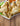 12 crispy samosas are piled together on a white plate. A samosa in front is cut open and inside is some ground beef with pieces of vegetables.